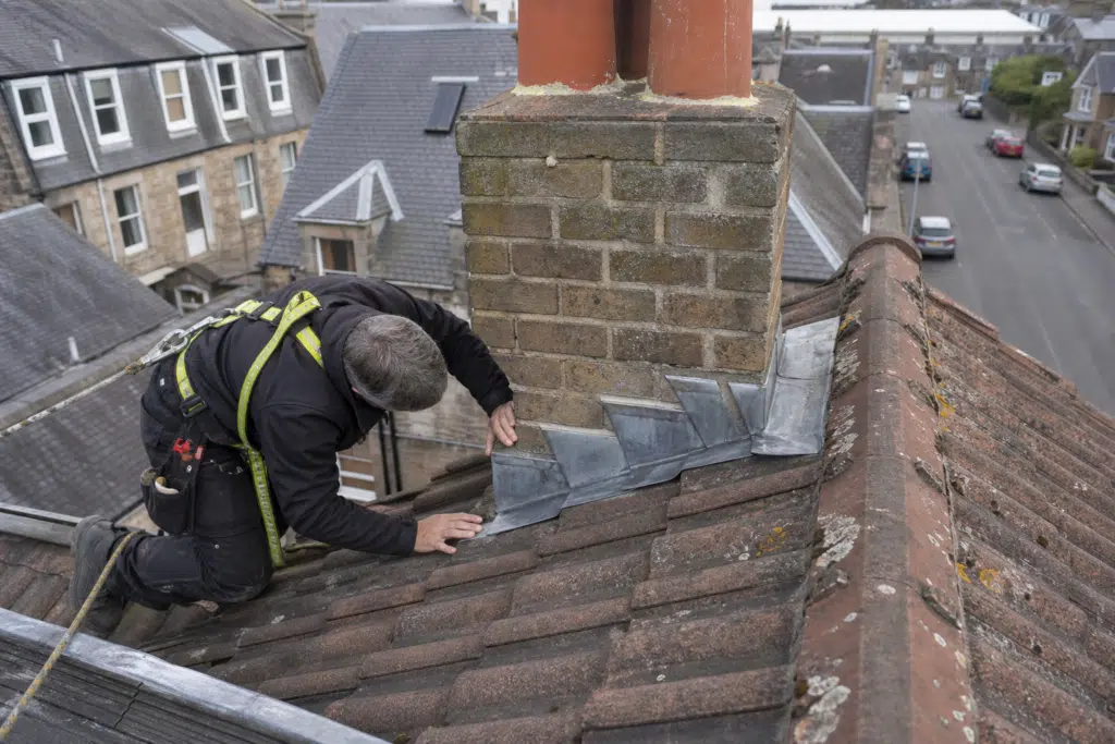 Professional inspection of a tiled residential roof near chimney leadwork in Dundee