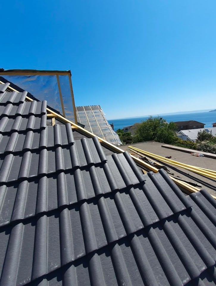 New dark grey roof tiles being installed on a residential property